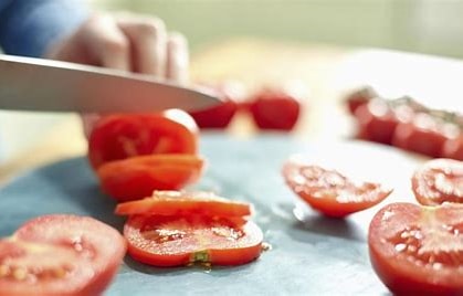Knife slicing ripe tomatoes